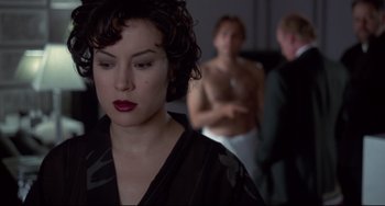 Movie still from “Bound” (1996), directed by Lilly Wachowski – A woman with red lipstick is standing in front of two men; Close Up shot, Over the shoulder angle