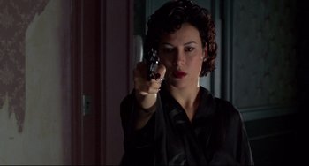 Movie still from “Bound” (1996), directed by Lilly Wachowski – A woman holding a gun in a room; Close Up shot, Low angle