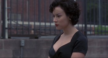 Movie still from “Bound” (1996), directed by Lilly Wachowski – A woman in a black dress is looking to her left; Close Up shot, Over the shoulder angle