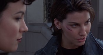 Movie still from “Bound” (1996), directed by Lilly Wachowski – A woman with a black shirt and a black jacket; Close Up shot, Over the shoulder angle