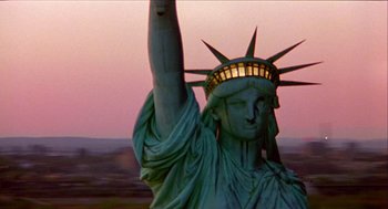 Movie still from “Bowling for Columbine” (2002), directed by Michael Moore – The statue of liberty is lit up at sunset; Extreme Wide shot, Low angle