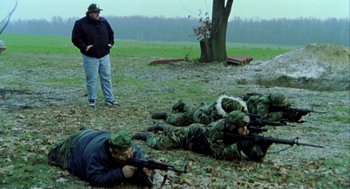 Movie still from “Bowling for Columbine” (2002), directed by Michael Moore – A group of men in camouflage uniforms with guns in a field; Wide shot, High angle