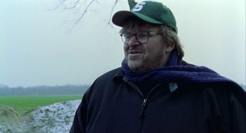 Movie still from “Bowling for Columbine” (2002), directed by Michael Moore – A person wearing glasses and a hat; Close Up shot, Over the shoulder angle