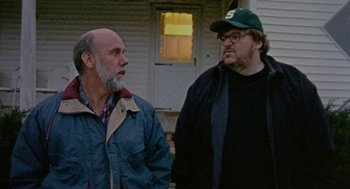 Movie still from “Bowling for Columbine” (2002), directed by Michael Moore – Two men standing next to each other in front of a house; Close Up shot, Over the shoulder angle