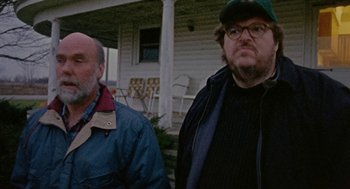 Movie still from “Bowling for Columbine” (2002), directed by Michael Moore – Two men standing in front of a house in front of a building; Close Up shot, Low angle