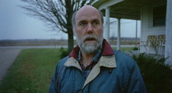 Movie still from “Bowling for Columbine” (2002), directed by Michael Moore – An older man with a beard and a blue jacket; Close Up shot, Low angle