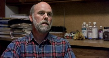 Movie still from “Bowling for Columbine” (2002), directed by Michael Moore – A man with a beard wearing a blue and red plaid shirt; Close Up shot, Over the shoulder angle