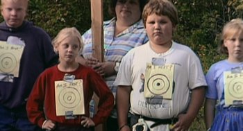 Movie still from “Bowling for Columbine” (2002), directed by Michael Moore – Three people are standing in front of a target; Medium shot, High angle