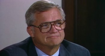 Movie still from “Bowling for Columbine” (2002), directed by Michael Moore – An older man wearing glasses and a suit; Close Up shot, High angle