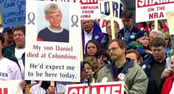 Movie still from “Bowling for Columbine” (2002), directed by Michael Moore – A group of people holding up signs in front of a crowd of people; Medium shot, High angle