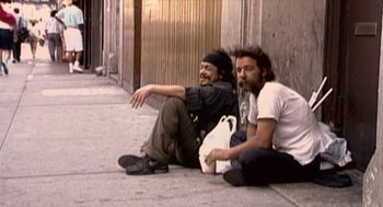 Movie still from “Bowling for Columbine” (2002), directed by Michael Moore – A couple of men sitting on the side of a road; Wide shot, High angle