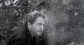 Movie still from “Bowling for Columbine” (2002), directed by Michael Moore – An old black and white photo of a man looking at the camera; Medium shot, Low angle