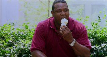 Movie still from “Bowling for Columbine” (2002), directed by Michael Moore – A man in a red shirt is eating a sandwich; Medium shot, Low angle