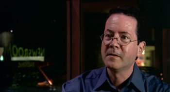 Movie still from “Bowling for Columbine” (2002), directed by Michael Moore – A person wearing glasses and a blue shirt; Close Up shot, High angle
