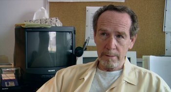 Movie still from “Bowling for Columbine” (2002), directed by Michael Moore – An older man with a beard and mustache wearing a tan jacket; Close Up shot, Over the shoulder angle