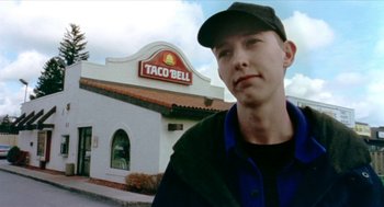 Movie still from “Bowling for Columbine” (2002), directed by Michael Moore – A man standing in front of a taco bell restaurant; Close Up shot, Low angle