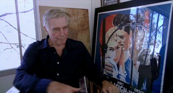Movie still from “Bowling for Columbine” (2002), directed by Michael Moore – An older man looking at an old movie poster; Medium shot, Over the shoulder angle
