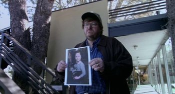 Movie still from “Bowling for Columbine” (2002), directed by Michael Moore – A man holding up a picture of himself and a girl; Close Up shot, High angle