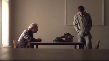Movie still from “Boy A” (2007), directed by John Crowley – Two men sitting at a table in front of a wall; Wide shot, Over the shoulder angle