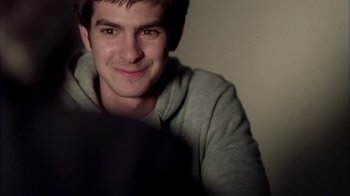 Movie still from “Boy A” (2007), directed by John Crowley – A young man is smiling for the camera while looking at a laptop; Close Up shot, Over the shoulder angle