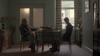 Movie still from “Boy A” (2007), directed by John Crowley – Two people sitting at a table in a room; Wide shot, Over the shoulder angle