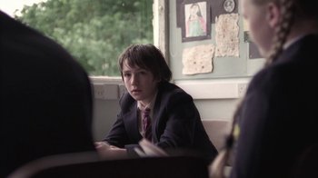 Movie still from “Boy A” (2007), directed by John Crowley – A boy in a suit sitting in front of a laptop; Medium shot, Over the shoulder angle