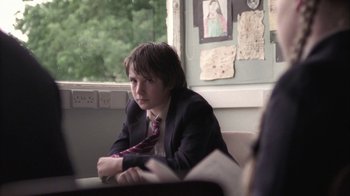 Movie still from “Boy A” (2007), directed by John Crowley – A person sitting in front of a window wearing a suit and tie; Medium shot, Over the shoulder angle