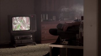 Movie still from “Boy A” (2007), directed by John Crowley – A person sitting on a chair in a living room; Medium shot, Over the shoulder angle