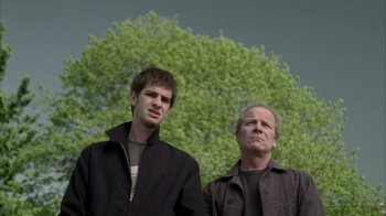 Movie still from “Boy A” (2007), directed by John Crowley – Two men standing next to each other in front of a tree; Medium shot, Low angle