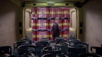 Movie still from “Boy A” (2007), directed by John Crowley – A man standing in front of a room filled with barrels; Wide shot, High angle