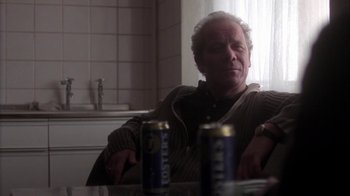 Movie still from “Boy A” (2007), directed by John Crowley – A man sitting at a table with two cans of sodas in front of him; Medium shot, Low angle