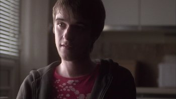 Movie still from “Boy A” (2007), directed by John Crowley – A young man in a red t - shirt and a gray jacket; Close Up shot, Over the shoulder angle
