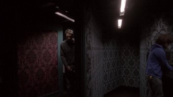 Movie still from “Boy A” (2007), directed by John Crowley – A man standing in a room with a wall covered in wallpaper; Wide shot, Low angle