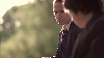 Movie still from “Boy A” (2007), directed by John Crowley – A man in a suit and tie looking at the camera; Close Up shot, Over the shoulder angle
