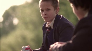 Movie still from “Boy A” (2007), directed by John Crowley – A boy in a suit and tie is holding a can of soda; Close Up shot, Over the shoulder angle