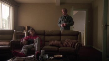 Movie still from “Boy A” (2007), directed by John Crowley – Two people sitting on a couch in a living room; Wide shot, Low angle