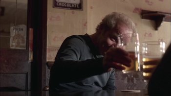 Movie still from “Boy A” (2007), directed by John Crowley – An older man is drinking a glass of wine; Medium shot, Low angle