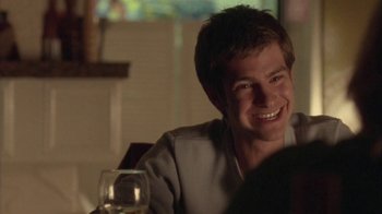 Movie still from “Boy A” (2007), directed by John Crowley – A young man smiles while sitting in front of a glass of wine; Close Up shot, Over the shoulder angle