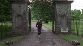 Movie still from “Boy A” (2007), directed by John Crowley – A man walking down a path through a gate; Wide shot, High angle