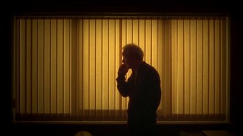 Movie still from “Boy A” (2007), directed by John Crowley – A man standing in front of a window with blinds; Medium shot, Low angle