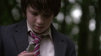 Movie still from “Boy A” (2007), directed by John Crowley – A boy in a suit and tie looking at a cell phone; Close Up shot, Low angle