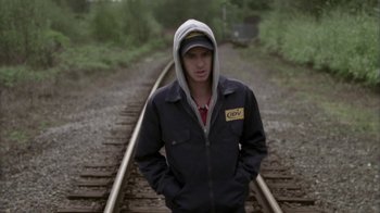 Movie still from “Boy A” (2007), directed by John Crowley – A young man standing on train tracks with his hands in his pockets; Medium shot, Low angle