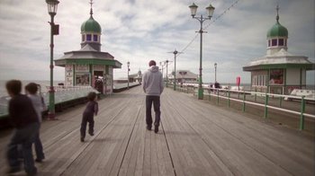Movie still from “Boy A” (2007), directed by John Crowley – A man and a child walking on a boardwalk; Wide shot, Low angle