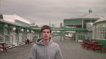 Movie still from “Boy A” (2007), directed by John Crowley – A young man in a gray hoodie standing in front of a building; Medium shot, Low angle