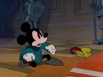 Movie still from “Brave Little Tailor” (1938), directed by Burt Gillett – A mickey mouse character is sitting on the ground; Wide shot, Over the shoulder angle