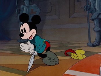 Movie still from “Brave Little Tailor” (1938), directed by Burt Gillett – A cartoon of a mickey mouse holding a knife in one hand; Medium shot, High angle