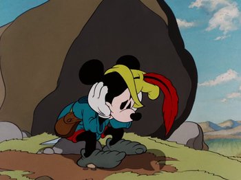 Movie still from “Brave Little Tailor” (1938), directed by Burt Gillett – A cartoon of a mickey mouse and pluto in a rocky area; Medium shot, Low angle