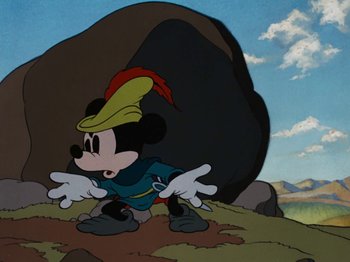 Movie still from “Brave Little Tailor” (1938), directed by Burt Gillett – A mickey mouse cartoon character in front of a rock; Wide shot, Low angle