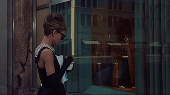 Movie still from “Breakfast at Tiffany's” (1961), directed by Blake Edwards – A woman in a black dress is looking in a store window; Medium shot, Over the shoulder angle