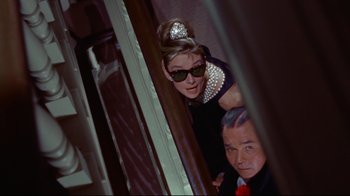 Movie still from “Breakfast at Tiffany's” (1961), directed by Blake Edwards – An older man and a young woman wearing sunglasses; Medium shot, Low angle